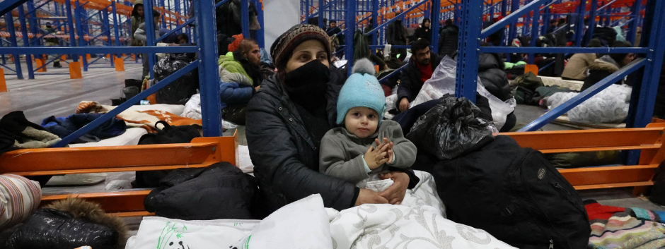 Migrantes refugiándose del frio en una caja de transportes en la frontera con Bielorrusia