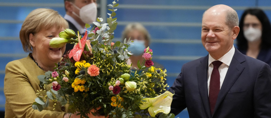 El nuevo canciller Olaf Scholz entrega un ramo de flores a Angela Merkel en su última reunión con el gabinete