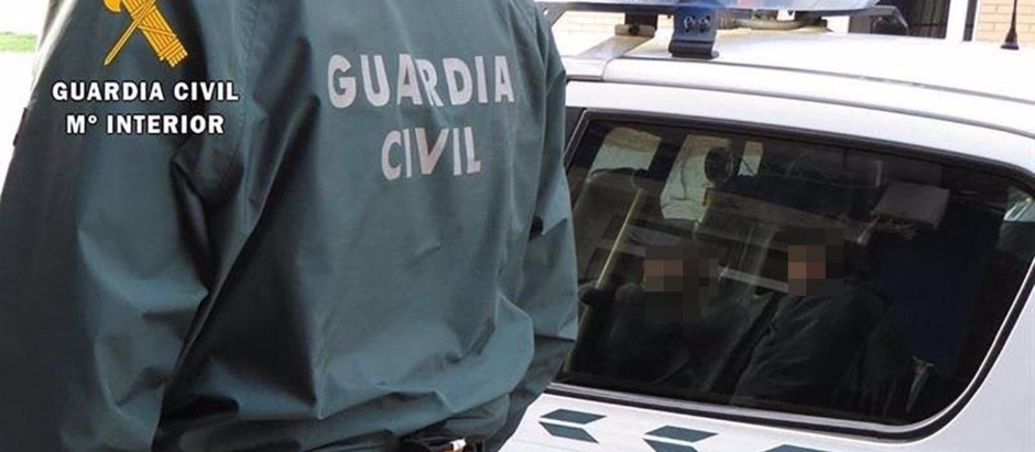 Un agente de la Guardia Civil junto a un coche patrulla.