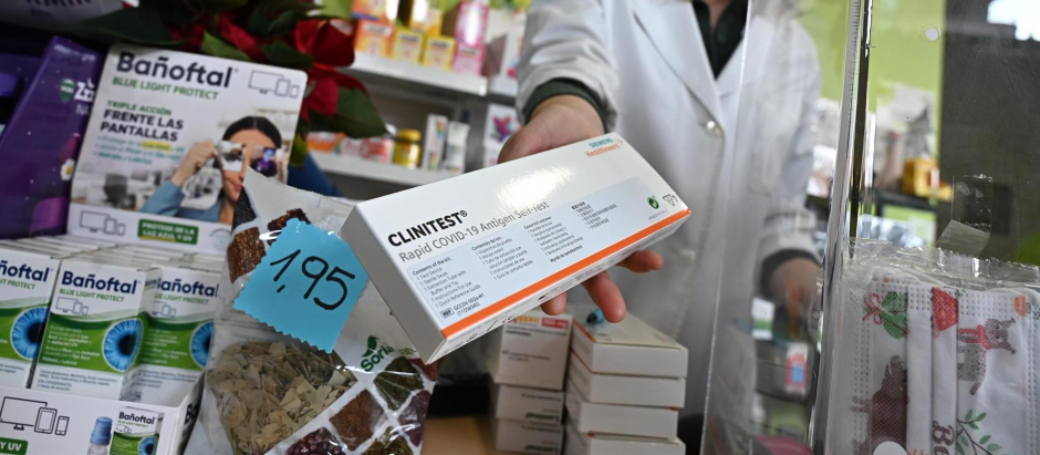 Una farmacéutica muestra una caja con test de antígenos