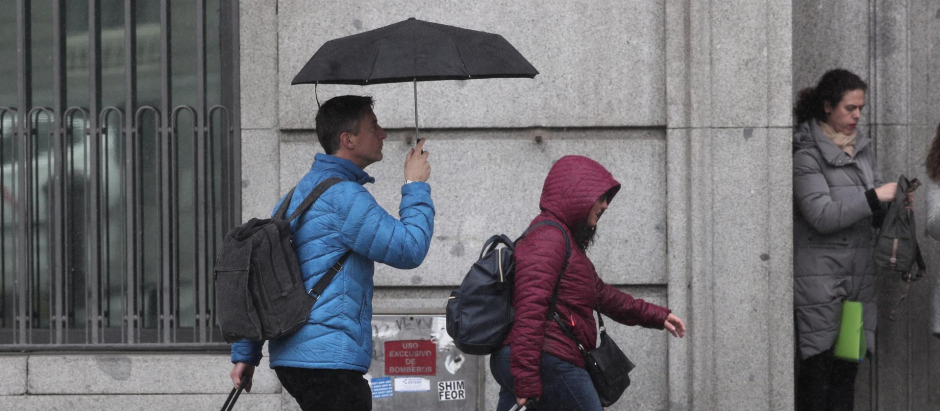 Dos turistas se refugian de la lluvia con paraguas, en Madrid en noviembre.