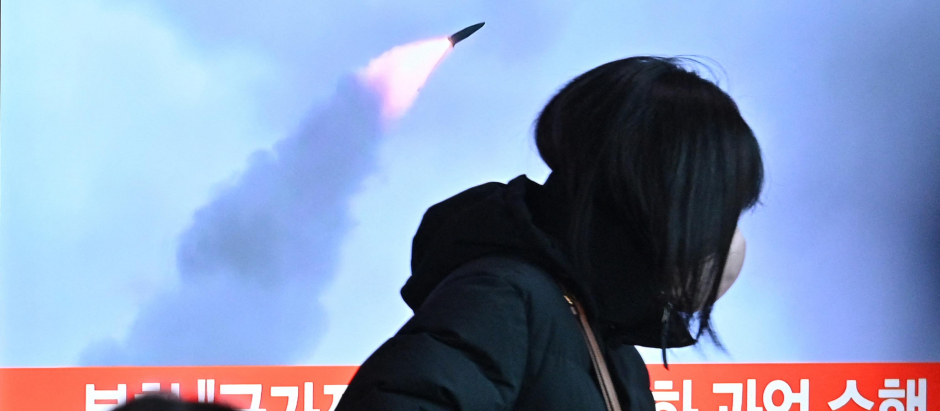 Una mujer pasa por delante de una pantalla donde se informa del lanzamiento