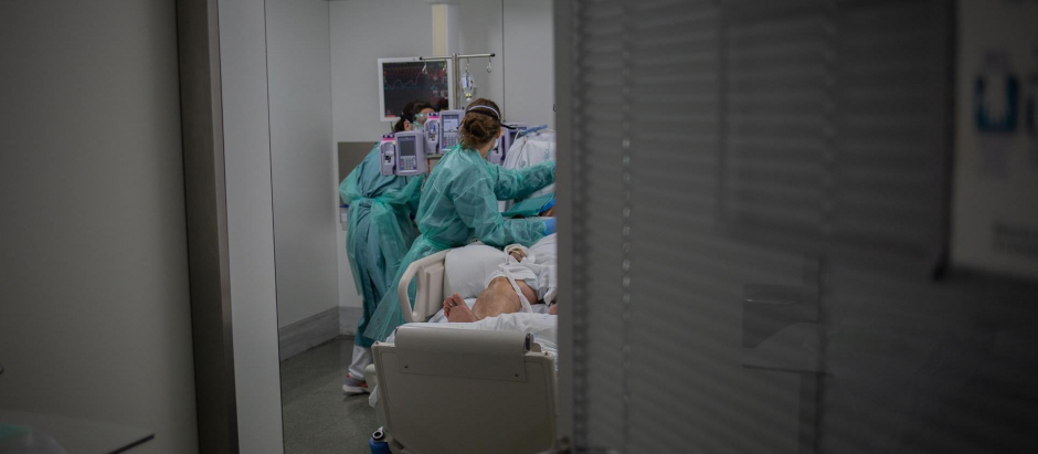 Personal sanitario visita a un enfermo ingresado en una habitación de una Unidad de Cuidados Intensivos