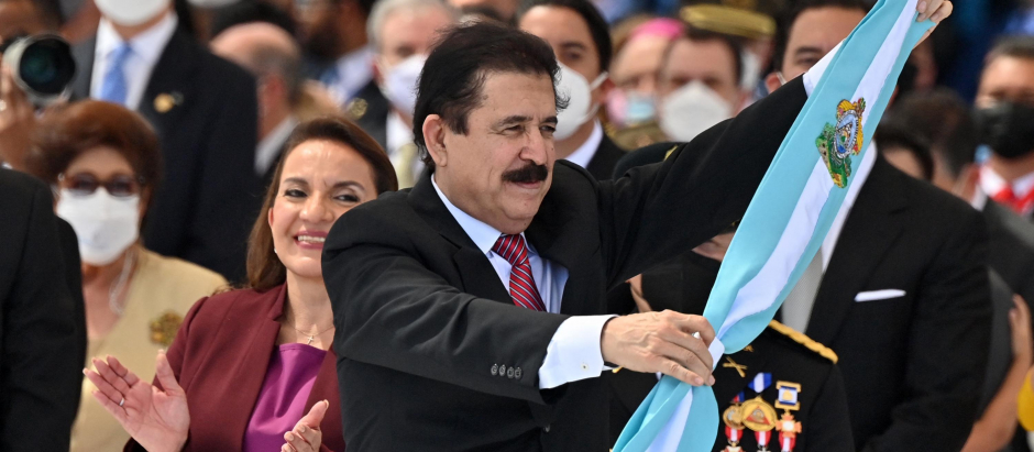El expresidente Manuel Zelaya y marido de Xiomara Castro (detrás) sostiene la banda presidencial que luego fue impuesta a la nueva presidenta de Honduras