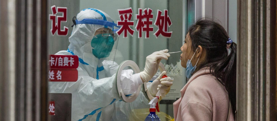 Un sanitario realiza una PCR a una mujer en China