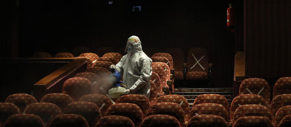 Un empleado sanitario desinfecta los asientos de una sala de cine en Nueva Delhi