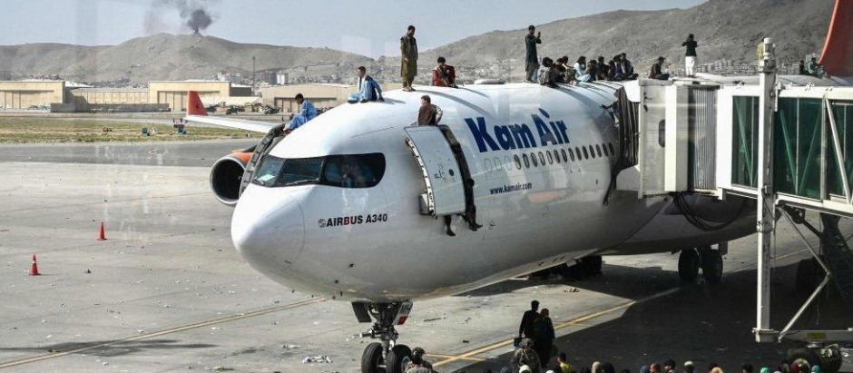 Ciudadanos afganos tratan de huir subidos a un avión, ante la llegada de los talibanes