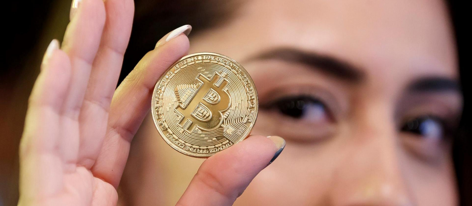 La cofundadora del Bitcoin Embassy Bar, Lorena Ortiz, muestra una moneda bitcoin
