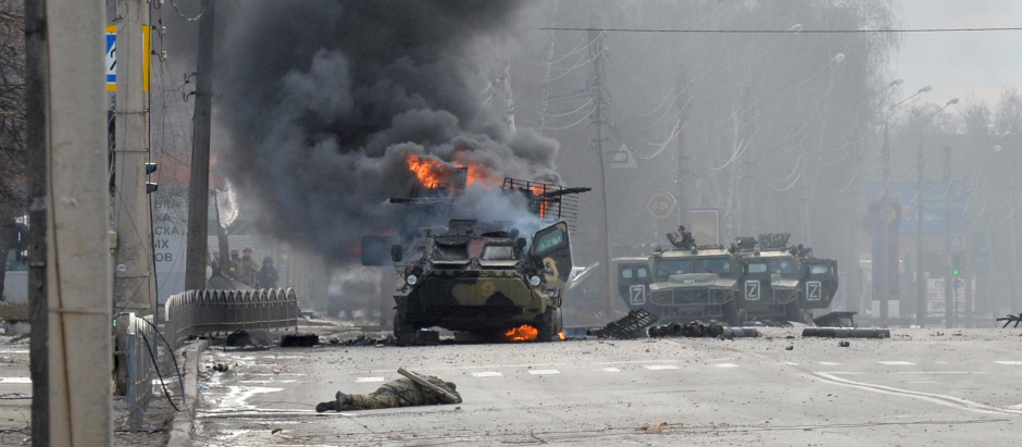 Un vehículo blindado ruso ardiendo junto al cuerpo de un soldado