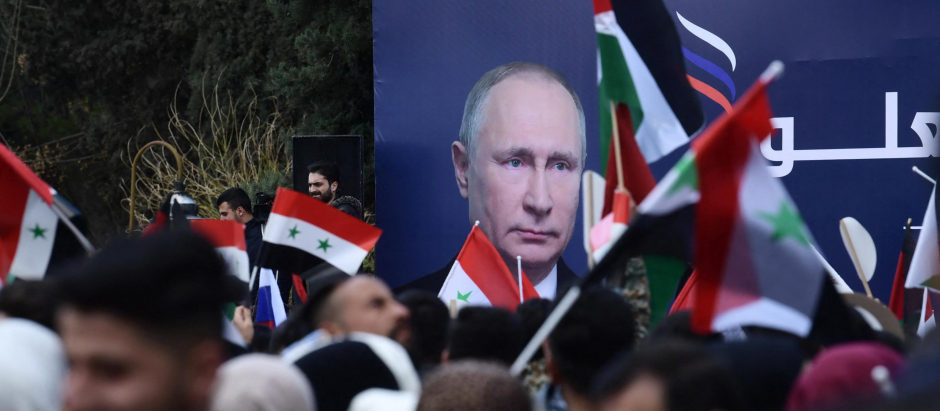 Un grupo de estudiantes sirios ondean banderas sirias, rusas y palestinas durante una manifestación a favor de la invasión rusa a Ucrania en la Universidad de Alepo, este jueves
