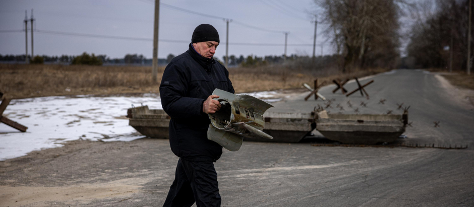 Un miembro de la defensa territorial ucraniana lleva un fragmento de misil