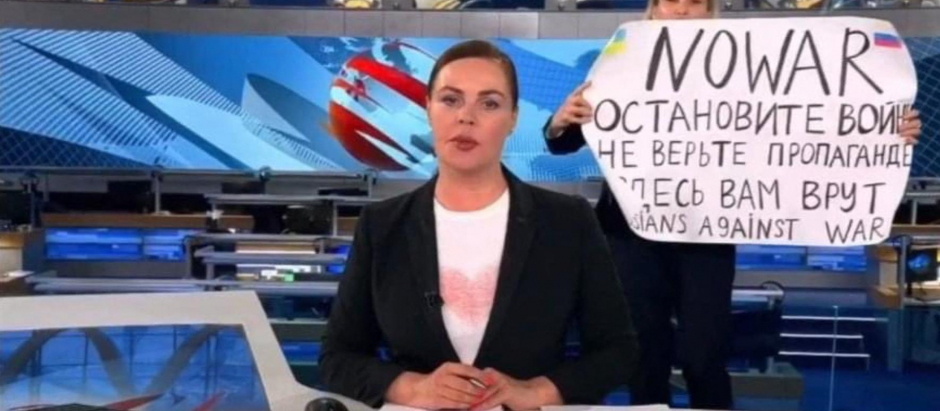 This video grab taken on March 15, 2022 shows Russian Channel One editor Marina Ovsyannikova holds a poster reading " Stop the war. Don't believe the propaganda. Here they are lying to you"  during on-air TV studio by news anchor Yekaterina Andreyeva , Russia's most-watched evening news broadcast, in Moscow on March 14, 2022 . - As a news anchor Yekaterina Andreyeva launched into an item about relations with Belarus, Marina Ovsyannikova, who wore a dark formal suit, burst into view, holding up a hand-written poster saying "No War" in English. (Photo by Handout / AFP) / RESTRICTED TO EDITORIAL USE - MANDATORY CREDIT "AFP PHOTO / Channnel One  - NO MARKETING NO ADVERTISING CAMPAIGNS - DISTRIBUTED AS A SERVICE TO CLIENTS