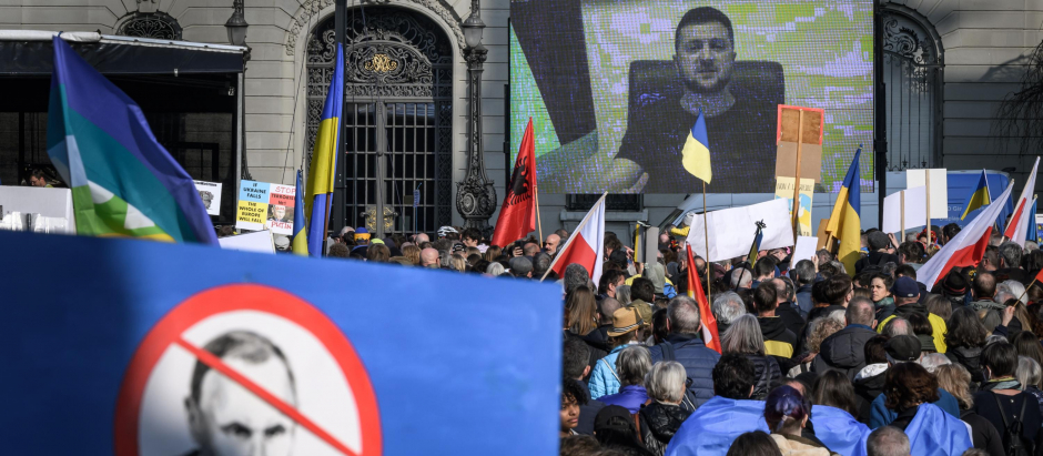 El presidente ucraniano, Volodymyr Zelensky, se muestra en una pantalla gigante después de entregar un mensaje de voz en vivo durante una manifestación contra la invasión rusa de Ucrania frente a la Cámara de Representantes de Suiza en Berna
