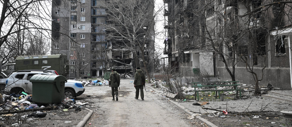 Dos soldados caminan entre edificios destruidos por los ataques rusos en Mariúpol