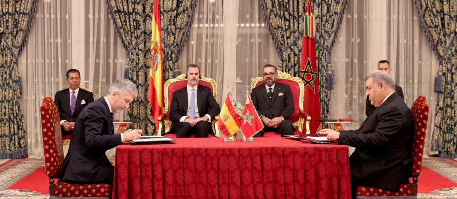 Felipe VI y Mohamed VI, y, en la mesa, el ministro del Interior, Fernando Grande-Marlaska, durante la firma del Convenio bilateral en materia de Lucha contra la Delincuencia entre los Ministerios de Interior de los dos países