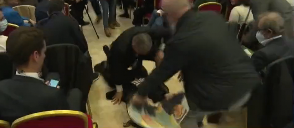 El momento en el que una espontánea es derribada tras enseñar una fotografía de Marine Le Pen con Putin en un acto de la derechista