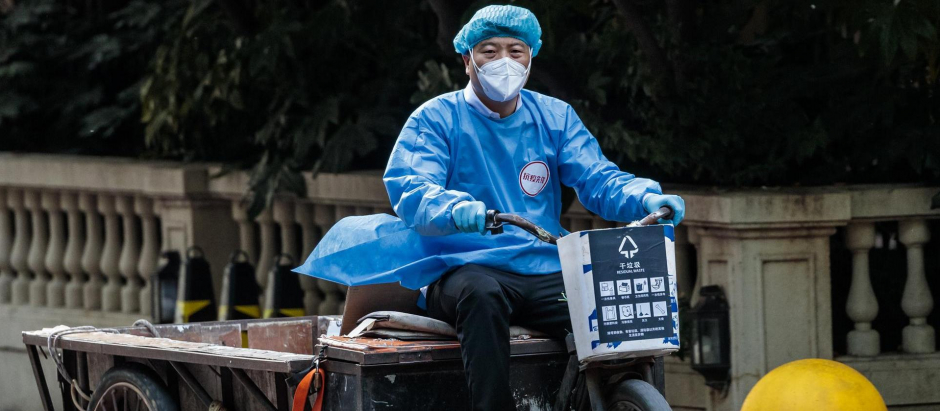 Un empleado de mantenimiento monta en bicicleta en una comunidad residencial bajo confinamiento en Shanghái