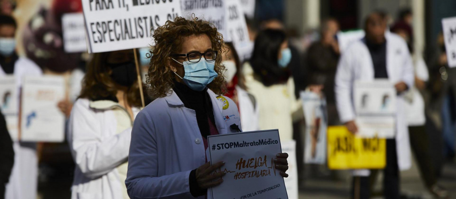 Una trabajadora sanitaria sostiene un cartel durante una concentración en la Puerta del Sol