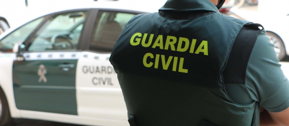 Un agente de la Guardia Civil, de espaldas, junto a un vehículo oficial