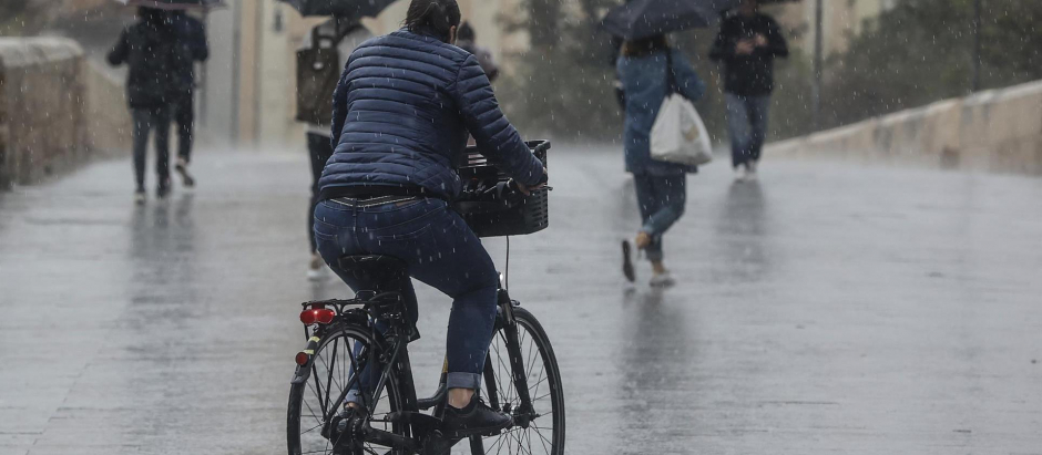 Una persona circula en bicicleta bajo la lluvia en Valencia