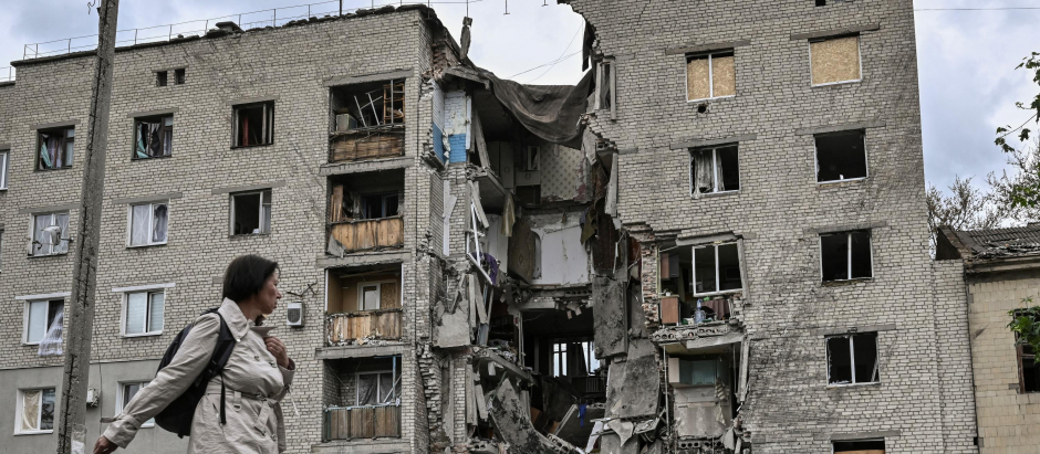 Una mujere camina frente a un edificio destrozado en Bakhmut, población del Donbás