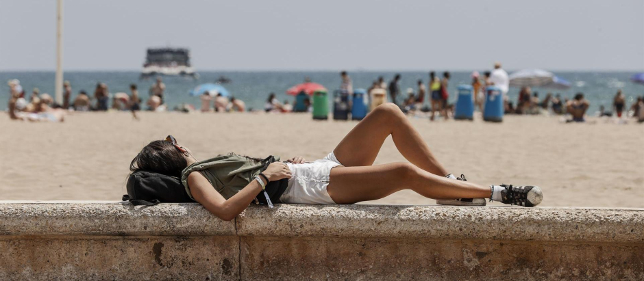 Una joven toma el sol en el paseo marítimo de la playa de La Malvarrosa (Valencia), este sábado