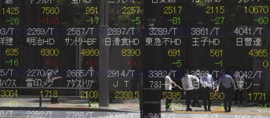 Los transeúntes se reflejan este lunes en un tablero de indicadores bursátiles en Tokio, Japón