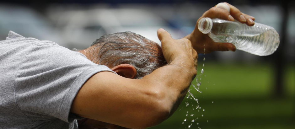 Un hombre se refresca con una botella de agua mientras camina por las calles del centro de Córdoba