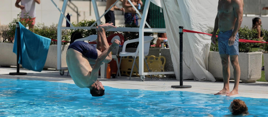 Un hombre se tira de cabeza al agua en la piscina municipal de Casa de Campo