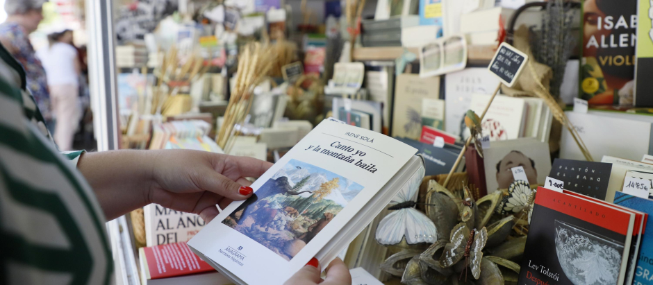 Una lectora examina un libro en la Feria del Libro de Madrid