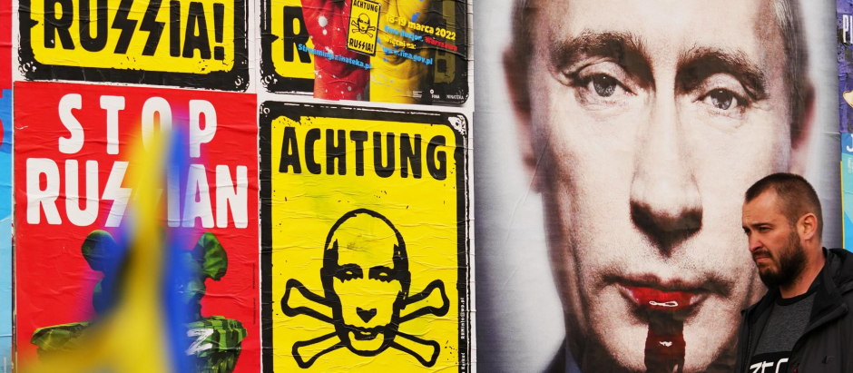 Un hombre pasa junto a una pared con carteles que representan al presidente ruso, Vladimir Putin, en Varsovia, Polonia