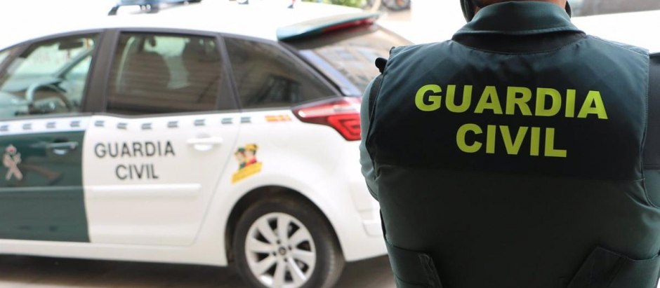 Un agente de la Guardia Civil junto a un coche patrulla