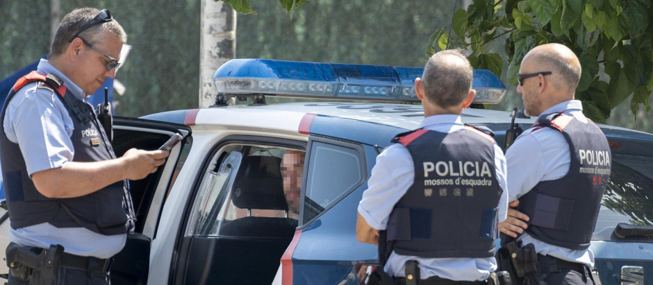 Varios mossos d'esquadra vigilan a un hombre detenido tras el asesinato de una mujer a cuchilladas en el municipio gerundense de Maçanet de la Selva