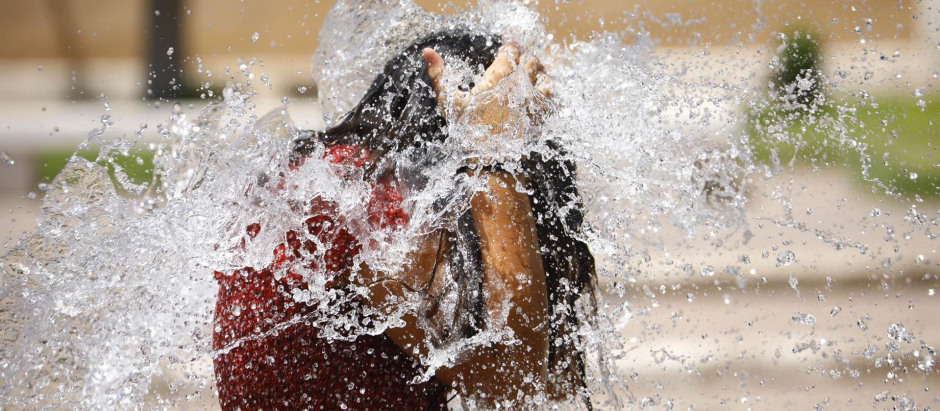 Una niña juega en una de las fuentes de Córdoba para aliviar las altas temperaturas este domingo