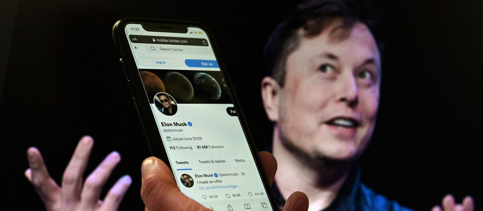 El magnate Elon Musk de fondo con su perfil de Twitter de frente