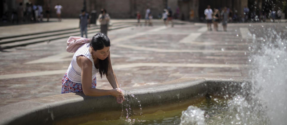 Una mujer se refresca en una fuente del centro histórico de Valencia.