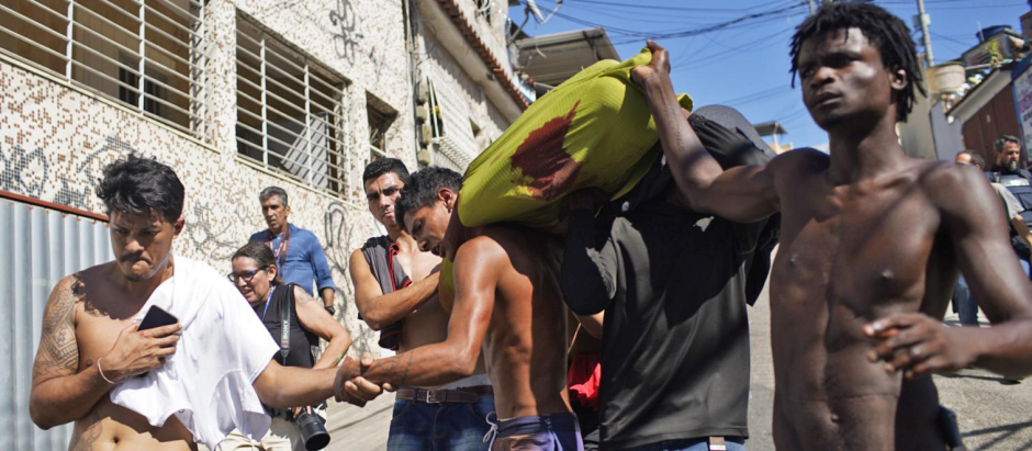 Residentes de la favela Complexo do Alemao cargan el cadáver de un hombre muerto durante una redada policial en Río de Janeiro, Brasil, el 21 de julio de 2022