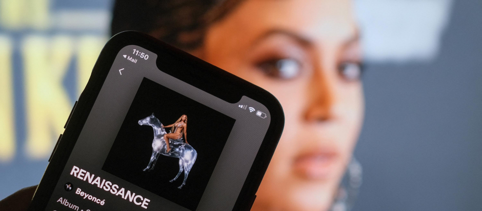 La portada de 'Renaissance', de Beyoncé, en un teléfono con una foto de la cantante al fondo