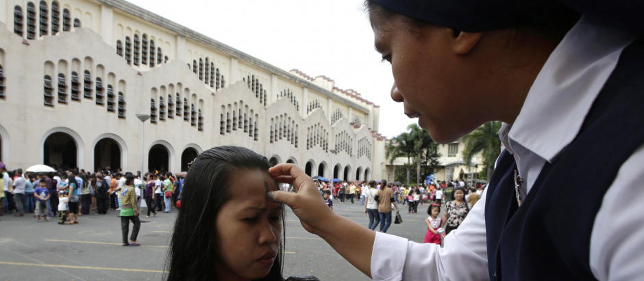 Una monja filipina realiza la señal de la cruz en la frente de una niña