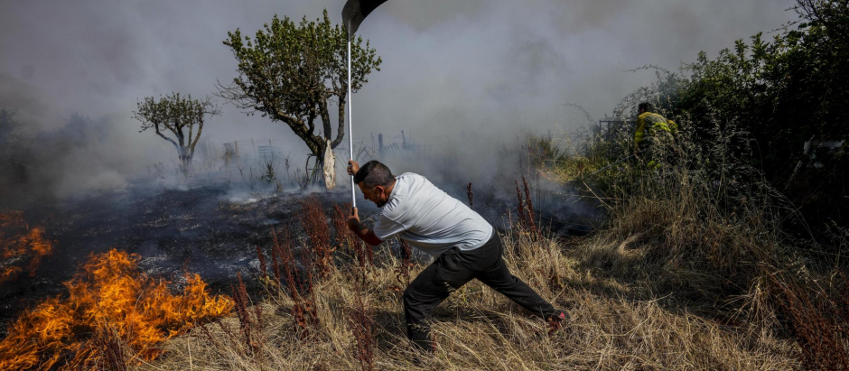 Un vecino de Tabara (Galicia) lucha contra un incendio con la ayuda de una pala, en julio