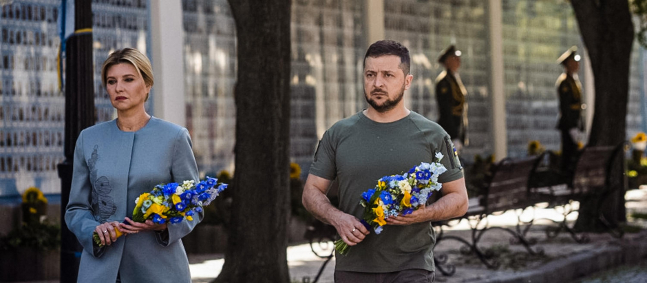 El presidente ucraniano Volodímir Zelenski (D) y su esposa Olena frente al muro conmemorativo de los militares ucranianos muertos durante la invasión rusa