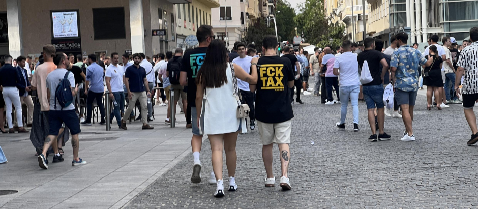 Dos asistentes a MundoCrypto con una camiseta en contra de los impuestos