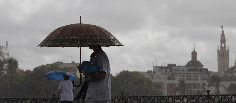Dos personas caminan bajo sus paraguas en Sevilla, este martes