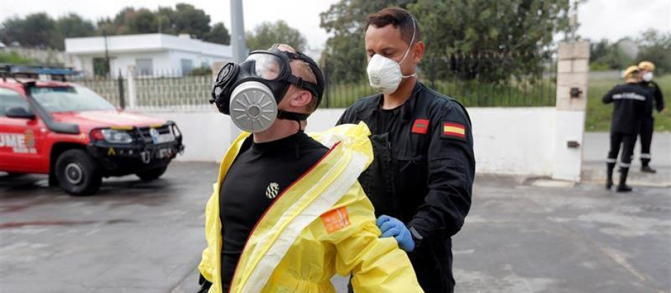Un soldado de la UME ayuda a quitarse el traje protector tras desinfectar una residencia durante la pandemia