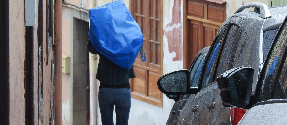 Una persona se protege de la lluvia con una bolsa de plástico durante una tormenta registrada en La Orotava, en Tenerife, este sábado