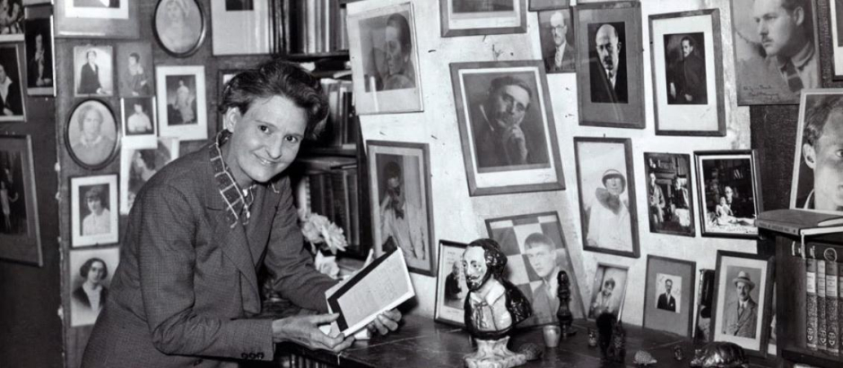 La librera y editora Sylvia Beach en su librería parisina, Shakespeare and Company, junto a las fotos de grandes escritores