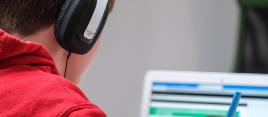 Un niño con auriculares, estudiando frente a su ordenador