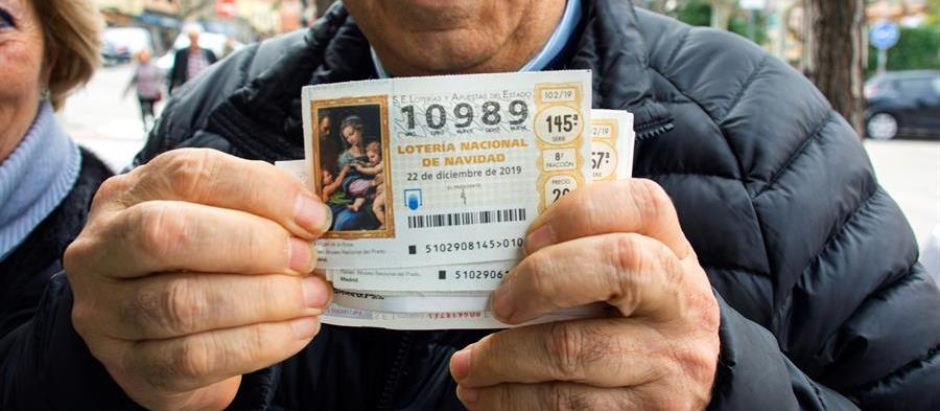 Un hombre sostiene un décimo premiado de la Lotería de Navidad, en diciembre de 2019