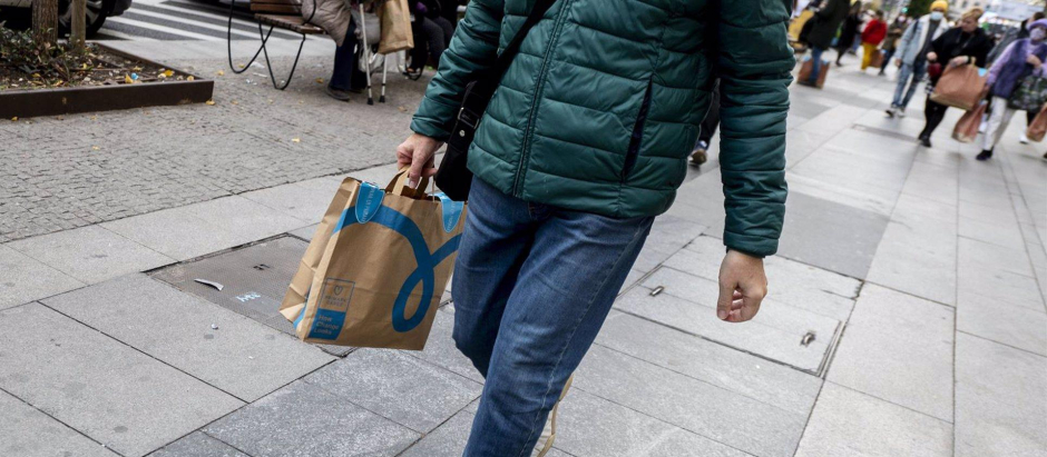 Un hombre camina con una bolsa con compra de un centro comercial