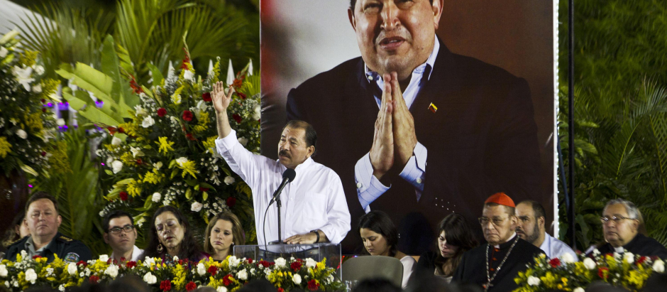 El dictador nicaragüense Daniel Ortega da un discurso con el retrato de Hugo Chavez